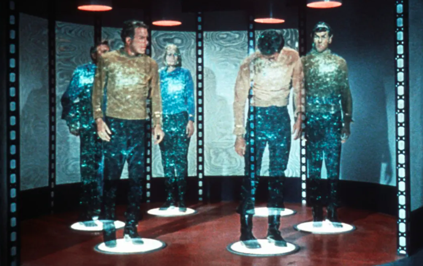 Screenshot from Star Trek (TOS) of five people on the transporter pads in the middle of dematerialization