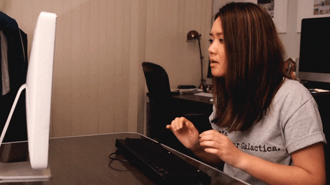 Gif of a woman and a hand coming out of a monitor doing a secret handshake