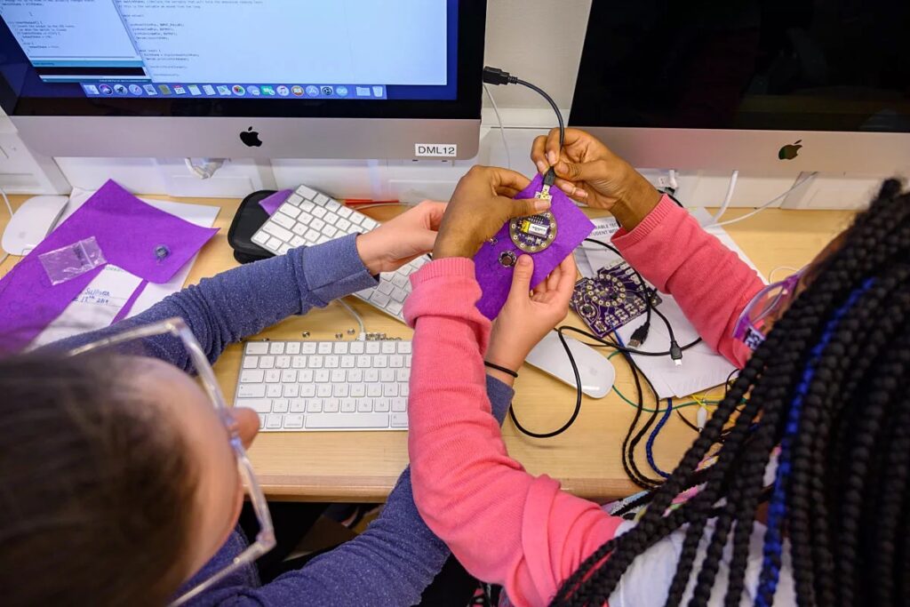Two girls are working at a computer and programming together
