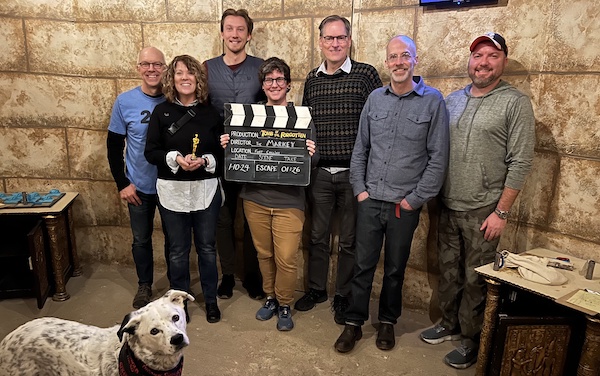 Seven Geeks plus Dipper the dog pose withe a sign proving they escaped from The Markey Escape Rooms.