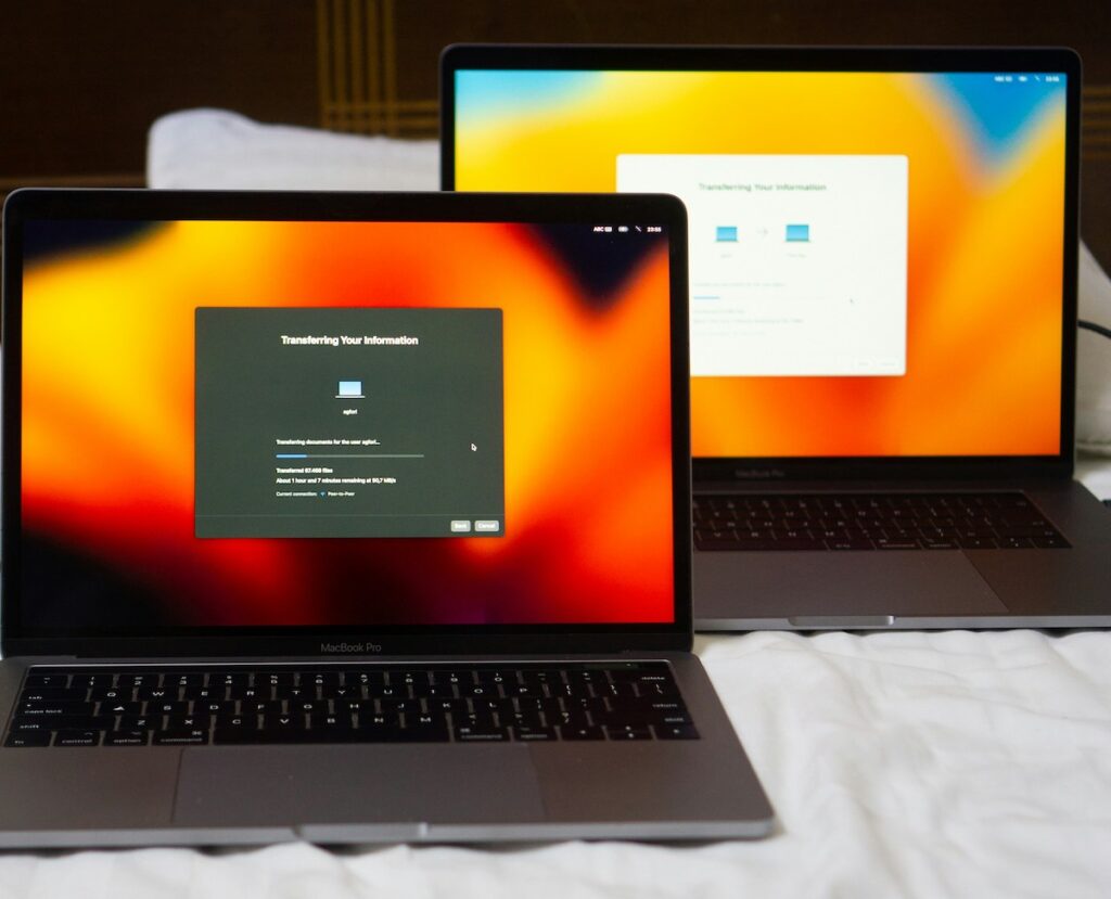 Two laptops sitting next to each other on a flat, white surface. The images on the screen are almost identical.